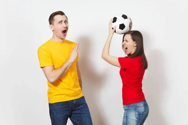 Divertente pazzo allegro europeo giovane coppia, donna, uomo, tifosi di calcio in giallo rosso uniforme tenere giocare a calcio isolato su sfondo bianco. Sport, calcio gioco, tempo libero famiglia, concetto di stile di vita . — Foto Stock