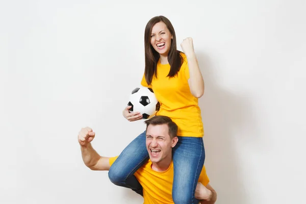 Натхненна молода пара, жінка сидить на людських плечах, фанати з футбольним м'ячем підбадьорюють улюблену футбольну команду, виражаючи жестикулюючі руки ізольовані на білому тлі. Сімейне дозвілля, концепція способу життя . — стокове фото