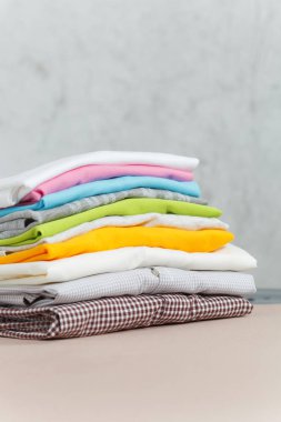 Çamaşırhane, yıkanmış renkli elbise Ütü, kazık kadar yakın aile giyim üzerine Ütü Masası beyaz arka plan üzerinde izole. Temizlik kavramı. Reklam için yer kopyalayın. Metin için yer.