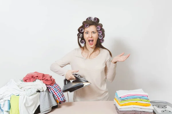 Distressed housewife with curlers on hair in light clothes ironi — Stock Photo, Image