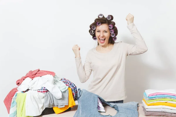 Divertente casalinga sorridente in abiti leggeri, bigodini sui capelli con indumenti di famiglia non restrinti, camicia bruciata fatta da ferro su asse da stiro. Donna isolata su sfondo bianco. Copia spazio per pubblicità . — Foto Stock