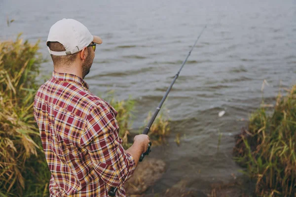 Πίσω όψη αξύριστος νεαρός με ένα καλάμι ψαρέματος στο καρώ shi — Φωτογραφία Αρχείου