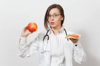 Beautiful young doctor woman with stethoscope isolated on white background. Female doctor in medical gown holding red apple piece of pizza. Healthcare personnel health concept Choice proper nutrition. clipart