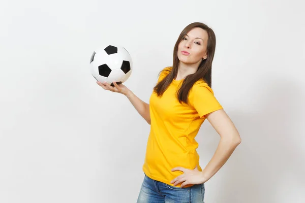Beautiful European young cheerful happy woman, football fan or player in yellow uniform holding soccer ball isolated on white background. Sport, play football, health, healthy lifestyle concept.