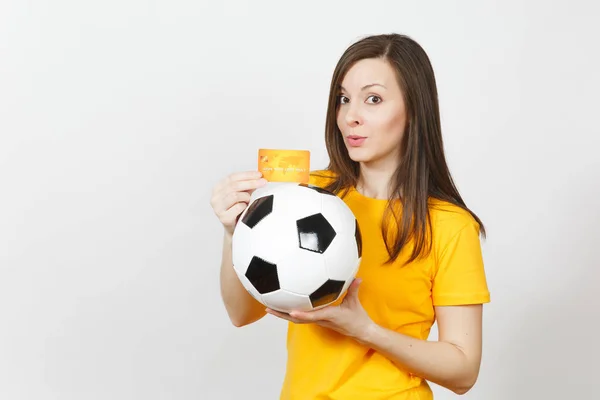 Hermosa joven europea alegre mujer, fanático del fútbol o jugador en uniforme amarillo con tarjeta de crédito pelota de fútbol aislado sobre fondo blanco. Deporte, juego de fútbol, emoción concepto de estilo de vida . — Foto de Stock
