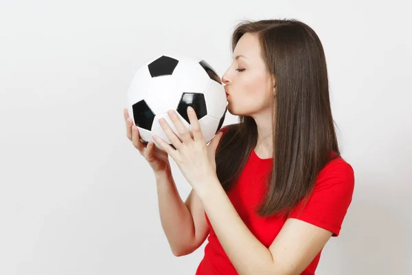 Beautiful European young cheerful happy woman, football fan or player in red uniform hold kiss classic soccer ball isolated on white background. Sport play football, health, healthy lifestyle concept.
