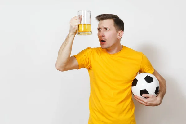 Inspirado joven diversión desconcertado hombre europeo, ventilador o jugador en uniforme amarillo sostener jarra de cerveza pelota de fútbol animar equipo de fútbol favorito aislado sobre fondo blanco. Deporte, juego, estilo de vida concepto . — Foto de Stock