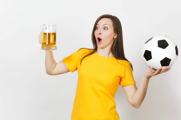 Hermosa joven europea alegre mujer, fanático del fútbol o jugador en uniforme amarillo sosteniendo jarra de cerveza, pelota de fútbol aislado sobre fondo blanco. Deporte, jugar al fútbol, concepto de estilo de vida saludable . —  Fotos de Stock