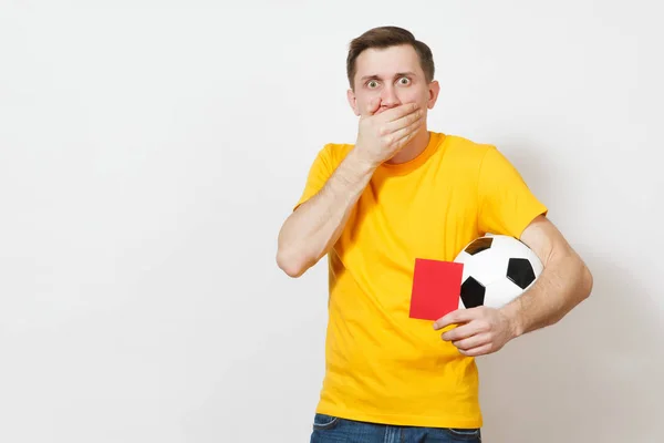 Triste sconvolto piangendo scioccato giovane uomo, tifoso di calcio o giocatore in uniforme gialla coprire bocca a mano tenere cartellino rosso per ritirarsi dal campo isolato su sfondo bianco. Sport gioco, stile di vita concetto . — Foto Stock