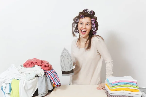 Young pretty housewife with curlers on hair in light clothes iro — Stock Photo, Image