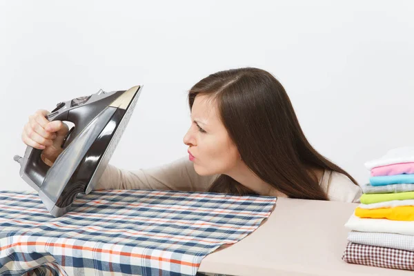 Close up casalinga sospetta in abiti leggeri stiratura marito camicia a scacchi, abbigliamento su asse da stiro con ferro da stiro. Donna isolata su sfondo bianco. Concetto di pulizia. Copia spazio annuncio . — Foto Stock