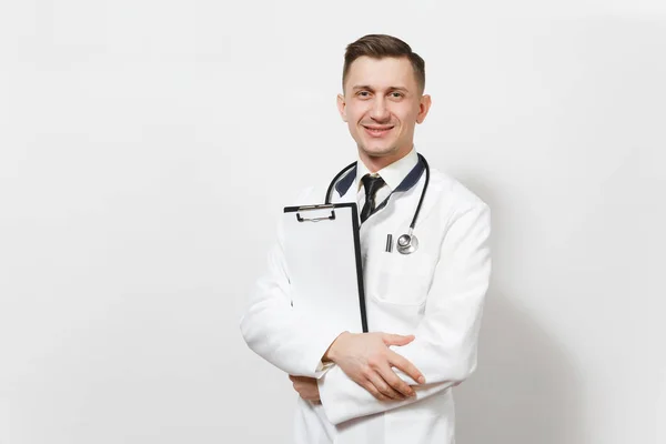 Sonriendo experimentado joven médico guapo aislado sobre fondo blanco. Médico masculino en uniforme médico, tarjeta de salud estetoscopio en la carpeta del bloc de notas. Personal sanitario, salud, concepto de medicina . — Foto de Stock