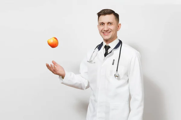 Uśmiechnięty mężczyzna młody lekarz na białym tle. Lekarz w medyczny stetoskop jednolite, rzucanie się czerwone jabłko. Pracowników służby zdrowia, zdrowia, medycyny pojęcie. Prawidłowe odżywianie. Miejsce. — Zdjęcie stockowe