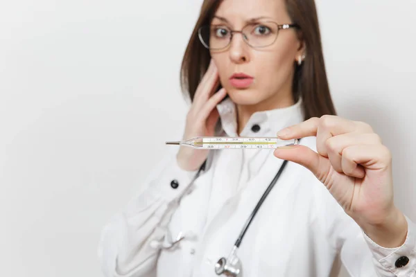 Stäng upp upprörd läkare kvinna i medicinsk klänning med stetoskop, glasögon. Fokusera på klinisk termometer med hög feber temperaturen isolerad på vit bakgrund. Vårdpersonal, medicin koncept. — Stockfoto