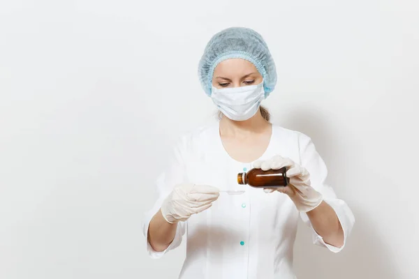 Medico donna in maschera viso, cappello sterile, guanti versare medicina liquida in cucchiaio da bottiglia isolata su sfondo bianco. Medico donna in abito medico. Personale sanitario, salute, concetto di medicina . — Foto Stock