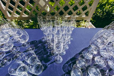 Parti için hazırlanıyor. Çok temiz parlak gözlük şarap, şampanya, viski, meyve suyu, su ve diğer içecekler masada çardak bahçede açık bir partide mavi bir masa örtüsü ile boş