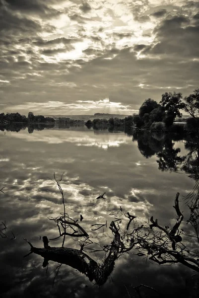 Pięknej przyrody. Sepia zdjęcie filtr zachmurzone niebo i drzewa wzdłuż brzegu rzeki są odzwierciedlane na powierzchni wody — Zdjęcie stockowe