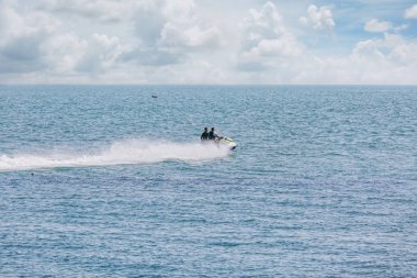 Büyük dalgalar oluşturan iki genç erkeklerde bir beyaz ve sarı su mavi denizde sürme loitering su sıçramalarına ve arka plan bulutlu gökyüzü üzerinde köpük