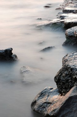 Sisli Nehri'nin güzel doğal kıyı peyzaj. Ön plan su içinde taşlar bir kalın beyaz sis ile kaplı
