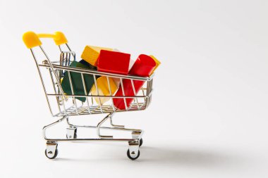 Süpermarket bakkal itme sepetinin sarı saplı çok renkli geometrik şekillerle beyaz arka plan üzerinde izole dolu alışveriş için kapatın. Alışveriş kavramı. Kopya alanı reklam için
