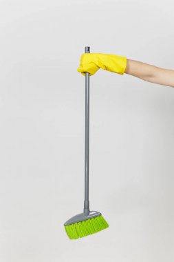 Kadın el sarı eldiven tutar uzun gri süpürge ile temizlik ve süpürme yeşil villus beyaz arka plan üzerinde izole kapatın. Temizlik malzemeleri kavramı. Kopya alanı reklam için
