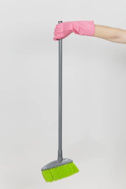 Pembe eldivenleri tutar uzun gri süpürge ile temizlik ve süpürme yeşil villus kadın el beyaz arka plan üzerinde izole kapatın. Temizlik malzemeleri kavramı. Kopya alanı reklam için