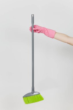 Pembe eldivenleri tutar uzun gri süpürge ile temizlik ve süpürme yeşil villus kadın el beyaz arka plan üzerinde izole kapatın. Temizlik malzemeleri kavramı. Kopya alanı reklam için
