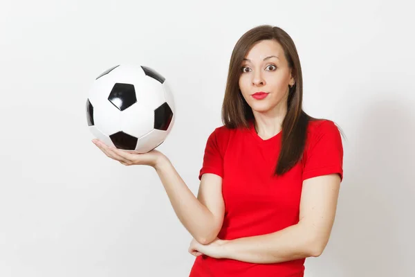 Pretty European young sad upset woman, football fan or player in red uniform holds soccer ball, worries about losing team isolated on white background. Sport, play football, lifestyle concept.