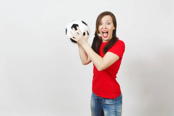 Joyeux jeune femme européenne, deux queues de cheval amusantes, fan de football ou joueur en uniforme rouge tenant ballon de football classique isolé sur fond blanc. Sport football santé, mode de vie sain concept . — Photo