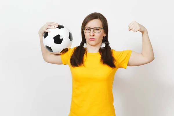Strong slim European woman, two fun pony tails, football fan or player in glasses, yellow uniform hold classic soccer ball isolated on white background. Sport play football, healthy lifestyle concept.