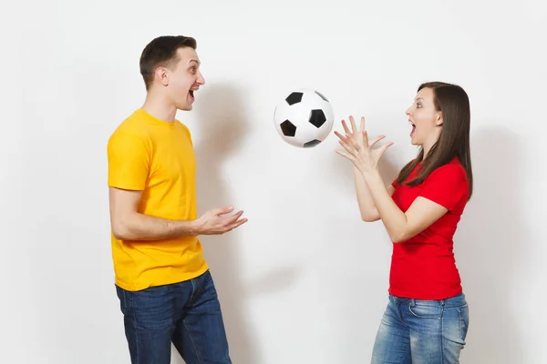 Divertente pazzo allegro europeo giovane coppia, donna, uomo, tifosi di calcio in giallo rosso uniforme tenere giocare a calcio isolato su sfondo bianco. Sport, calcio gioco, tempo libero famiglia, concetto di stile di vita . — Foto Stock