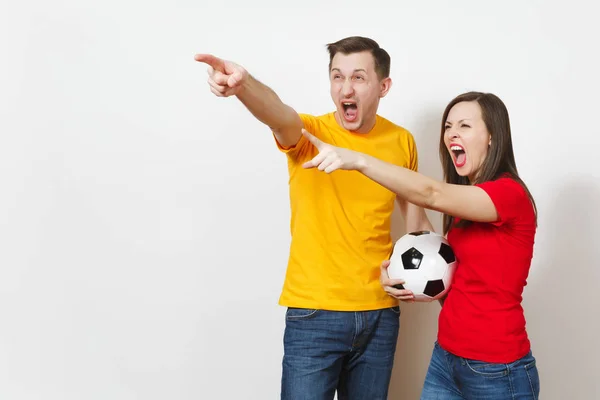 Грустная грустная молодая пара, женщина, мужчина, футбольные фанаты в желтой красной униформе с футбольным мячом развеселить команду заботы о потере команды изолированы на белом фоне. Спорт, семейный отдых, концепция образа жизни . — стоковое фото