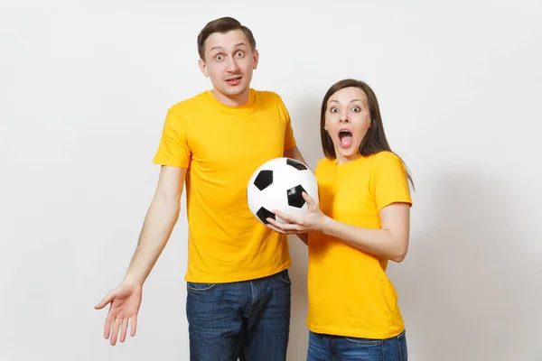 Весела весела емоційна молода пара, жінка, чоловік, шанувальники футболу в жовтій формі підбадьорюють команду підтримки з футбольним м'ячем ізольовано на білому тлі. Спорт, сімейне дозвілля, концепція способу життя . — стокове фото