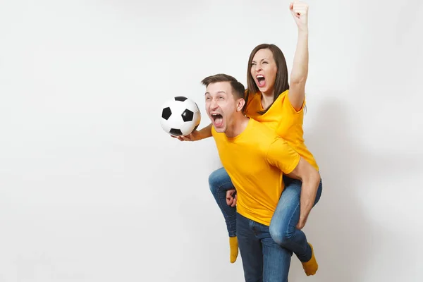 Ispirato giovane coppia, donna seduta su cavallino uomo, tifosi con pallone da calcio tifo preferito squadra di calcio espressivo gesticolando le mani isolate su sfondo bianco. Tempo libero in famiglia, concetto di stile di vita . — Foto Stock