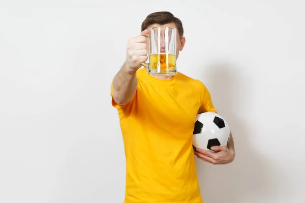Inspirado joven divertido hombre europeo, ventilador o jugador en uniforme amarillo celebrar en la cara delantera pinta taza de cerveza, fútbol bola animar equipo de fútbol favorito aislado sobre fondo blanco. Deporte, concepto de estilo . — Foto de Stock