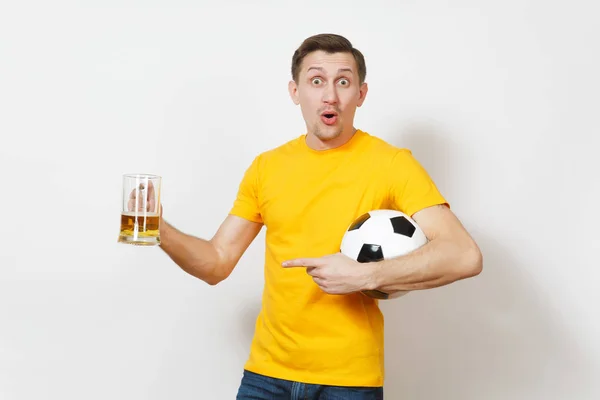 Inspirado joven divertido alegre hombre europeo, ventilador o jugador en uniforme amarillo sostener jarra de cerveza, pelota de fútbol animar equipo de fútbol favorito aislado sobre fondo blanco. Deporte, juego, estilo de vida concepto . — Foto de Stock