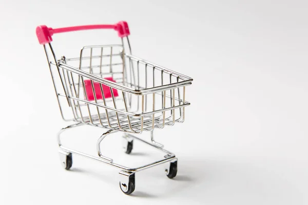 Κοντινό πλάνο της σούπερ μάρκετ σούπερ μάρκετ καροτσάκι για ψώνια με μαύρες ρόδες και ροζ πλαστικό στοιχεία στη λαβή που απομονώνονται σε λευκό φόντο. Έννοια της ψώνια. Αντίγραφο χώρος για διαφήμιση — Φωτογραφία Αρχείου