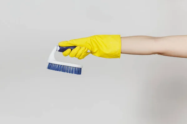 Primo piano di mano femminile in guanti gialli orizzontale tiene spazzola bianca con fibre dure per la pulizia con elementi blu isolati su sfondo bianco. Concetto di forniture di pulizia. Copia spazio per l'annuncio — Foto Stock