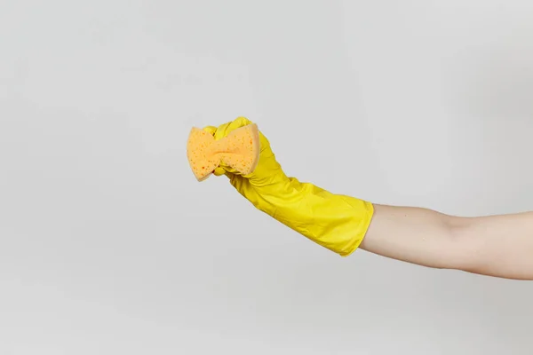 Close up da mão feminina em luvas amarelas segura e aperta esponja amarelo-laranja para limpar e lavar pratos isolados em fundo branco. Conceito de material de limpeza. Espaço de cópia para propaganda — Fotografia de Stock