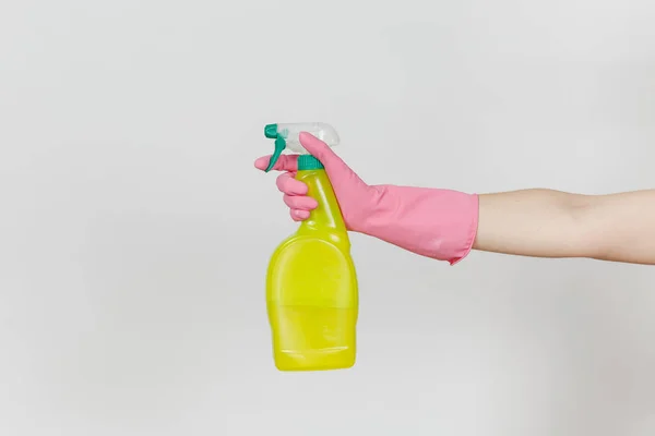 Close up of female hand in pink gloves click on yellow spray bottle with cleaner liquid with place for text isolated on white background. Cleaning supplies concept. Copy space for advertisement — Stock Photo, Image