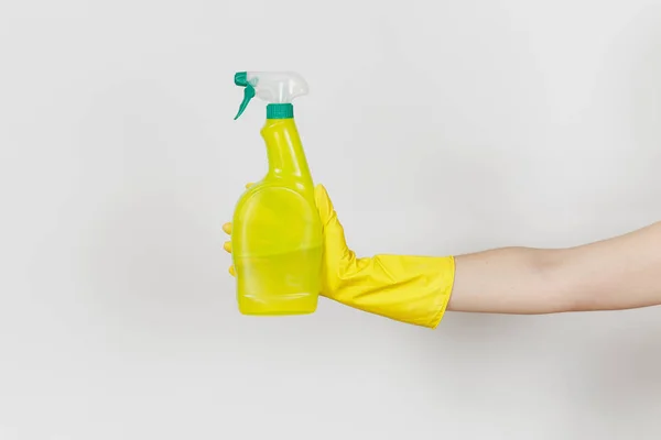 Primo piano della mano femminile in guanti gialli tiene bottiglia spray giallo con liquido detergente con posto per il testo isolato su sfondo bianco. Concetto di forniture di pulizia. Copia spazio per pubblicità — Foto Stock