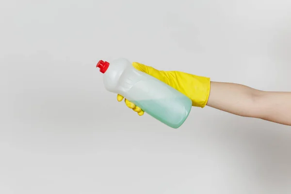 Close up de mão feminina em luvas amarelas mantém garrafa branca com líquido de limpeza verde para lavar pratos com lugar para texto isolado em fundo branco. Conceito de material de limpeza. Espaço de cópia para anúncio — Fotografia de Stock