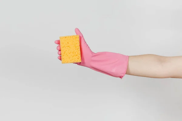 Close up of female hand in pink gloves horizontal holds yellow-orange sponge for cleaning and washing dishes isolated on white background. Cleaning supplies concept. Copy space for advertisement — Stock Photo, Image