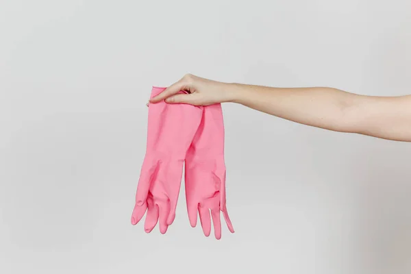 Close up da mão feminina segura um par de luvas rosa de borracha e látex para limpar e lavar pratos isolados em fundo branco. Conceito de material de limpeza. Espaço de cópia para propaganda — Fotografia de Stock