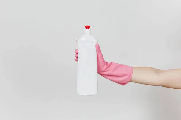 El primer plano de la mano femenina en guantes rosados sostiene la botella blanca con líquido más limpio para lavar los platos con lugar para el texto aislado sobre fondo blanco. Concepto de artículos de limpieza. Copiar espacio para anuncio — Foto de Stock
