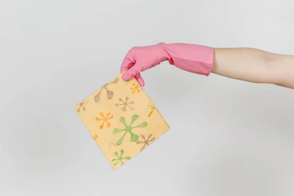 Zbliżenie ręka w różowe rękawiczki poziome posiada wzorzyste rag pomarańczowy do czyszczenia i mycia naczyń na białym tle. Czyszczenie koncepcji zaopatrzenia. Miejsce na reklamę — Zdjęcie stockowe