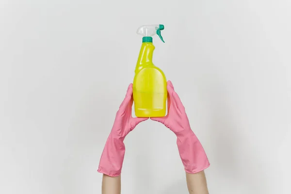 Close up van vrouwelijke handen in roze handschoenen verticaal gele spray fles met schonere vloeistof met plaats voor tekst geïsoleerd op een witte achtergrond houdt. Schoonmaak leveringen concept. Ruimte voor reclame kopiëren — Stockfoto