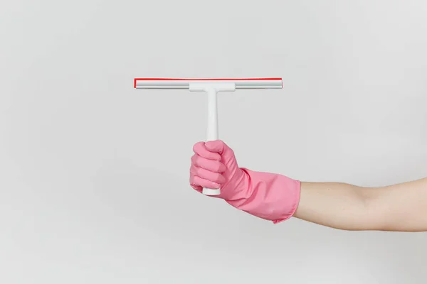 女性手在粉红色手套的关闭水平持有白色的刮刀表面清洗与红色元素隔离在白色背景。清洁用品的概念。复制广告空间 — 图库照片