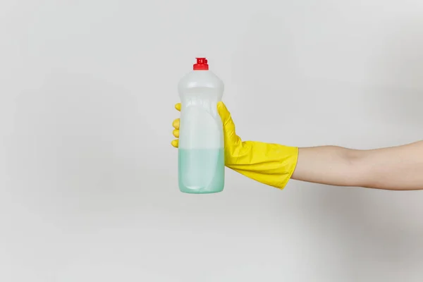 Nahaufnahme der weiblichen Hand in gelben Handschuhen hält weiße Flasche mit grünem Reinigungsmittel zum Geschirrspülen mit Platz für Text isoliert auf weißem Hintergrund. Reinigungsmittelkonzept. Kopierraum für Werbung — Stockfoto