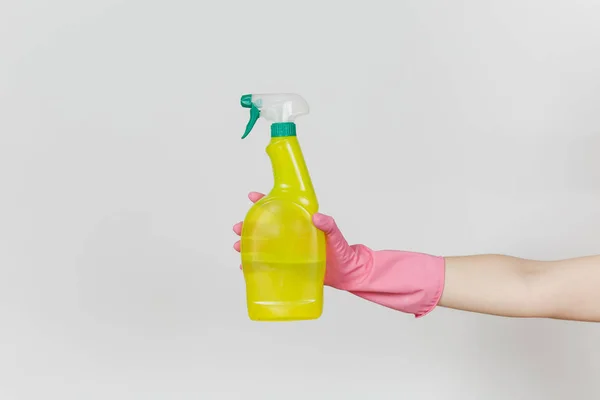 Primo piano della mano femminile in guanti rosa tiene bottiglia spray giallo con liquido detergente con posto per il testo isolato su sfondo bianco. Concetto di forniture di pulizia. Copia spazio per pubblicità — Foto Stock